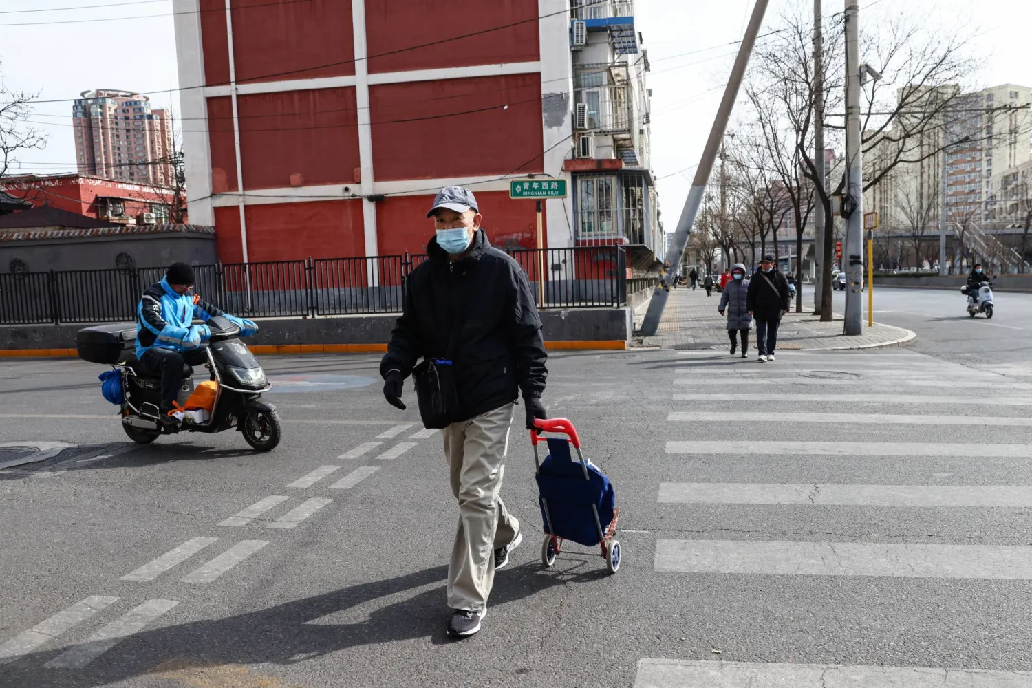 رجل مسن يرتدي قناع وجه بينما يسير في أحد شوارع بكين (إ.ب.أ)