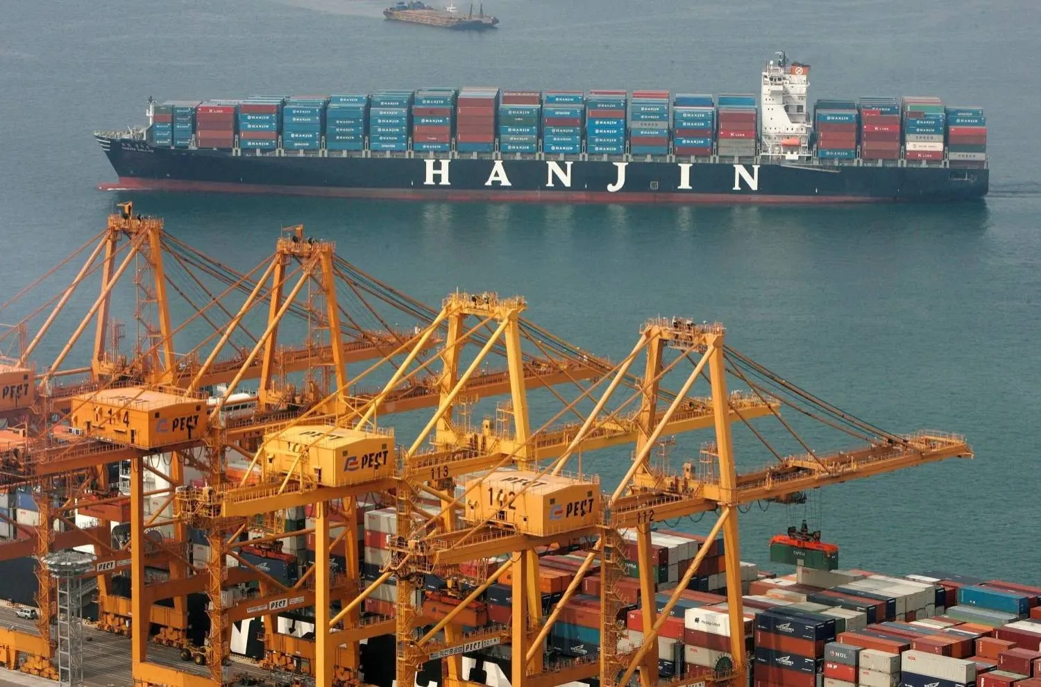 رافعات في أحد مواني الصين وتظهر سفينة أثناء المغادرة (رويترز)