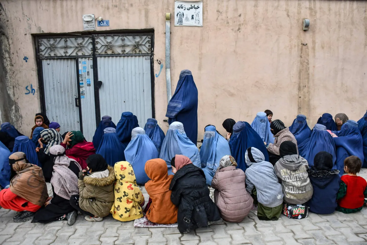 نساء وأطفال أفغان ينتظرون الحصول على مساعدات غذائية من مؤسسة خيرية محلية (أ.ف.ب)