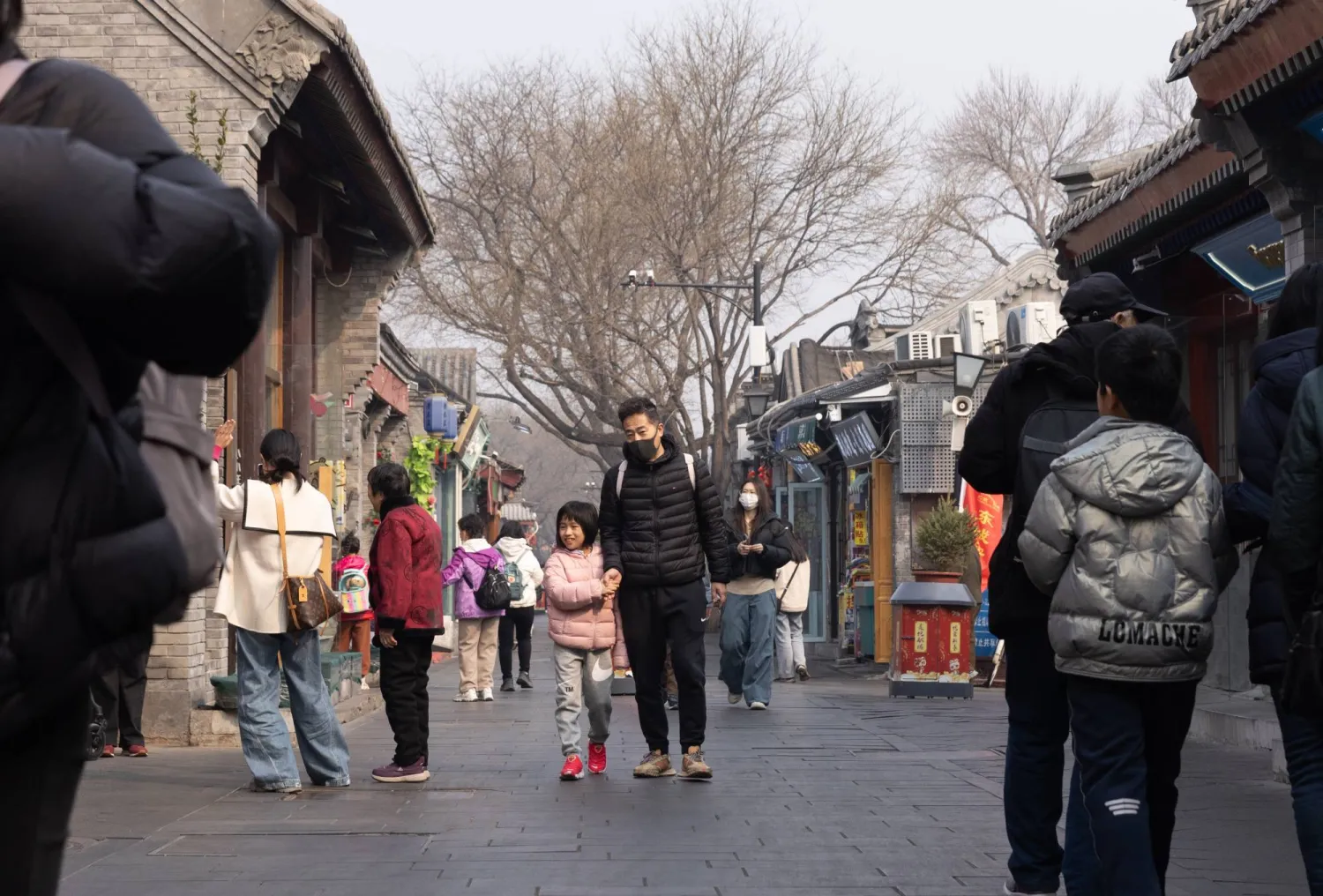 الناس يسيرون في شارع سياحي مزدحم ببكين (إ.ب.أ)