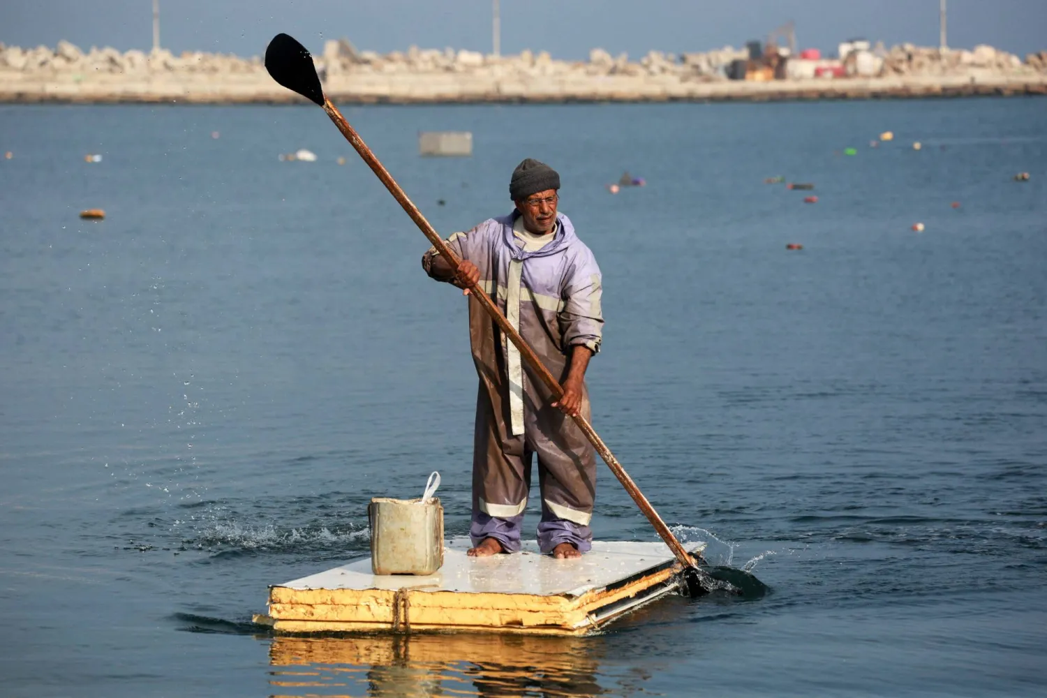 A Palestinian man uses the door of a refrigerator as a makeshift rowing boat to catch fish at the port of Gaza City on March 9, 2025.  (Photo by BASHAR TALEB / AFP)