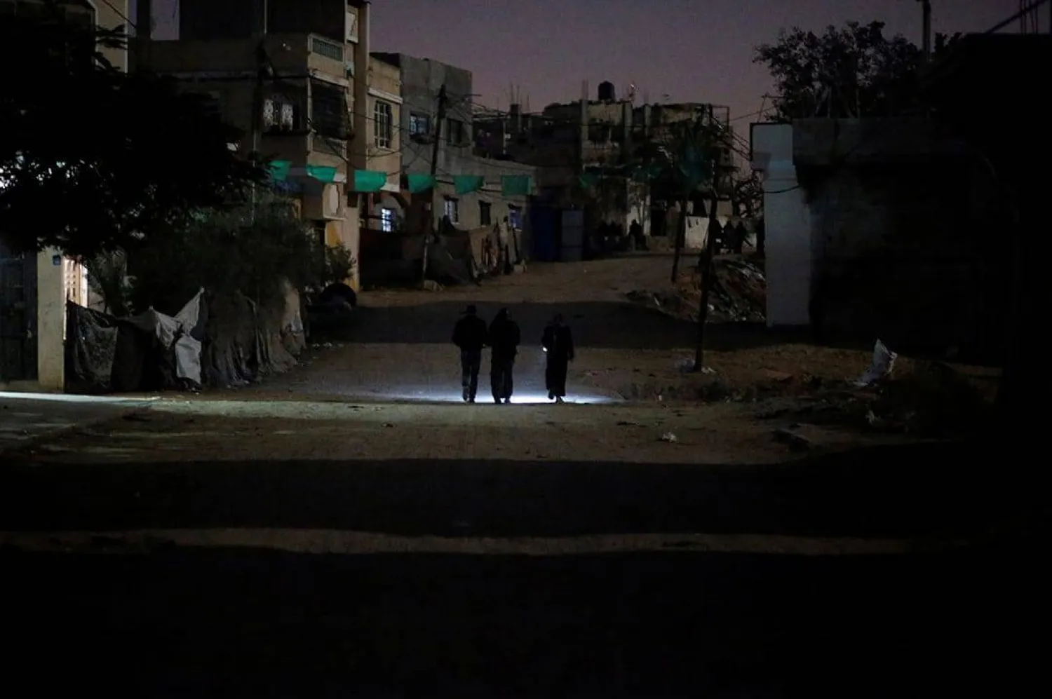 فلسطينيون يسيرون على الطريق أثناء انقطاع الكهرباء في بيت لاهيا شمال قطاع غزة... 12 يناير 2017 (رويترز)