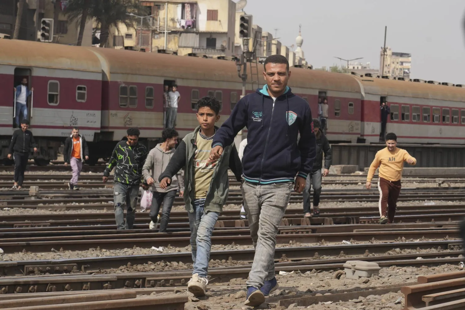 ركاب مصريون يعبرون خط السكة الحديد في منطقة شعبية بالقاهرة (أ.ب)