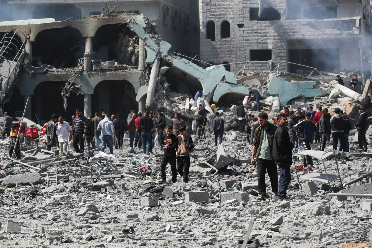 فلسطينيون يتفقدون الأضرار التي لحقت بمدرسة يلجأ إليها النازحون بعد قصف إسرائيلي في غزة (رويترز)