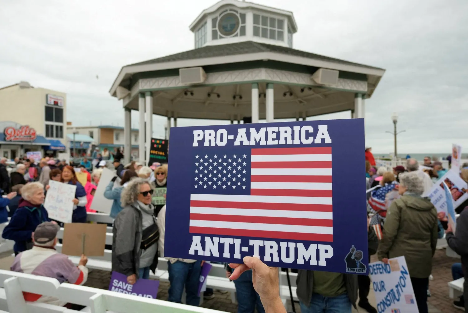 متظاهر يحمل لافتة «مع أميركا... ضد ترمب» خلال مسيرة احتجاجية ضد الرئيس الأميركي في ولاية ديلاوير (رويترز)