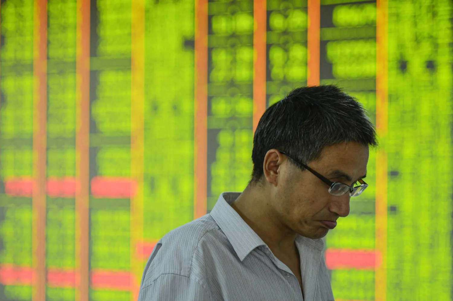 رجل يمر أمام شاشة تعرض تحركات سوق الأسهم بشركة أوراق مالية في هانغتشو بمقاطعة تشجيانغ شرق الصين (أ.ف.ب)