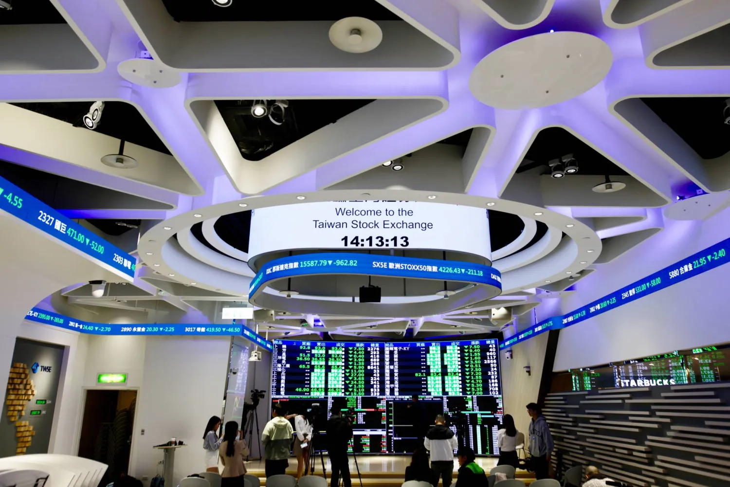 أشخاص يراقبون قيم الأسهم داخل مكتب بورصة تايوان في تايبيه (إ.ب.أ)