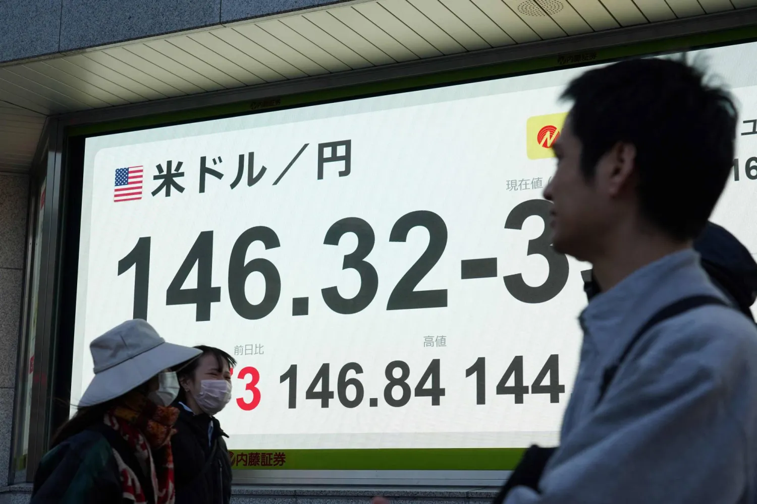 مشاة يمرون أمام شاشة إلكترونية تعرض حركة الأسهم في وسط العاصمة اليابانية طوكيو (أ.ف.ب)