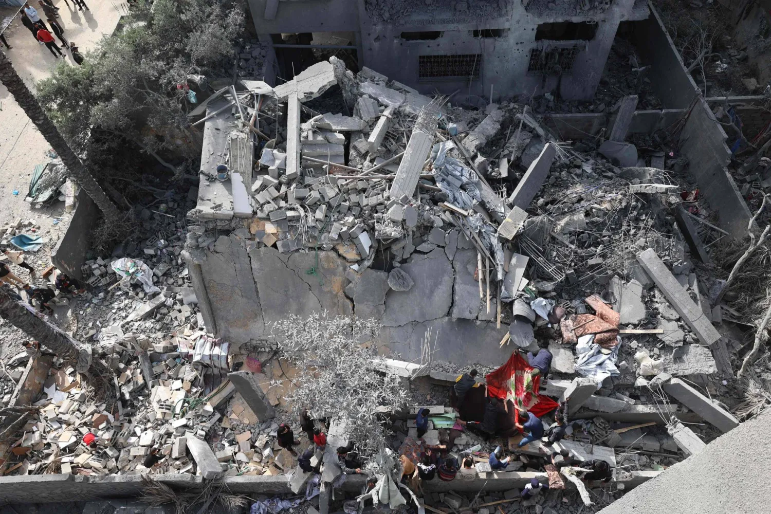 أشخاص يتفقدون الدمار في دير البلح وسط قطاع غزة في 7 أبريل 2025 بعد غارات جوية إسرائيلية ليلية (أ.ف.ب)