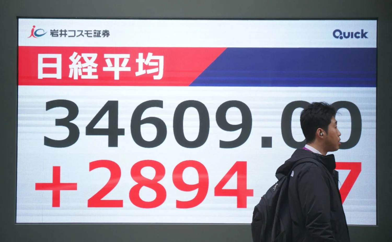 رجل يمر أمام شاشة تعرض حركة الأسهم في بورصة طوكيو بالعاصمة اليابانية (أ.ف.ب)