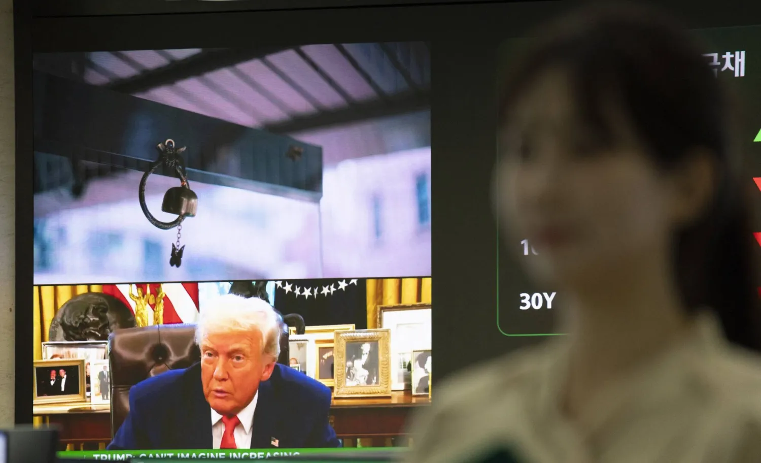 سيدة تظهر أمام شاشة تعرض صورة الرئيس الأميركي دونالد ترمب (إ.ب.أ)