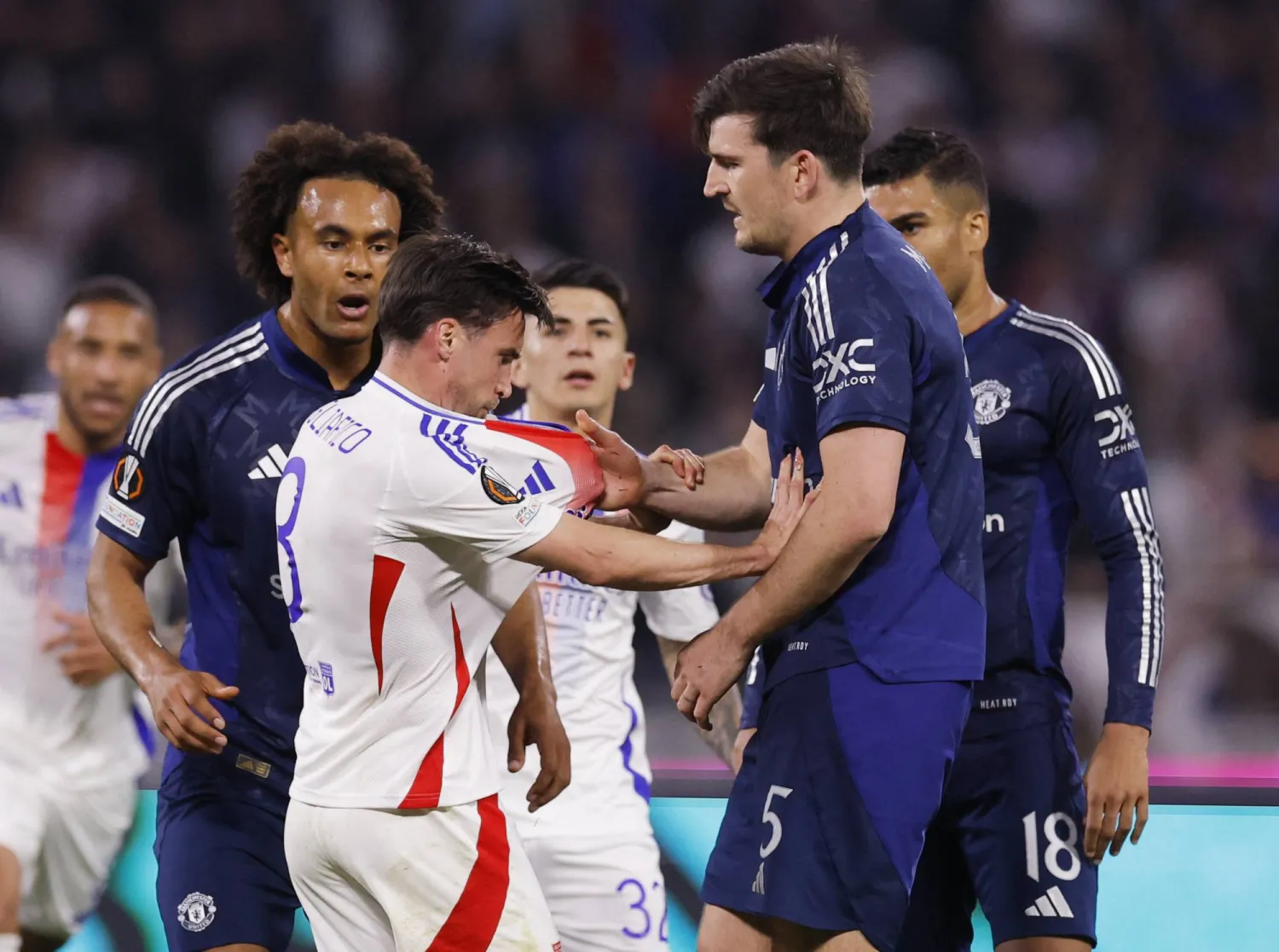 ماغواير لاعب مانشستر يونايتد يشتبك مع تاجليافيكو لاعب ليون خلال المباراة (رويترز)