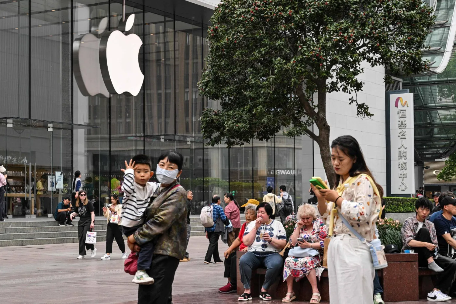 مشاة يسيرون أمام متجر شركة «أبل» في مدينة شنغهاي (أ.ف.ب)