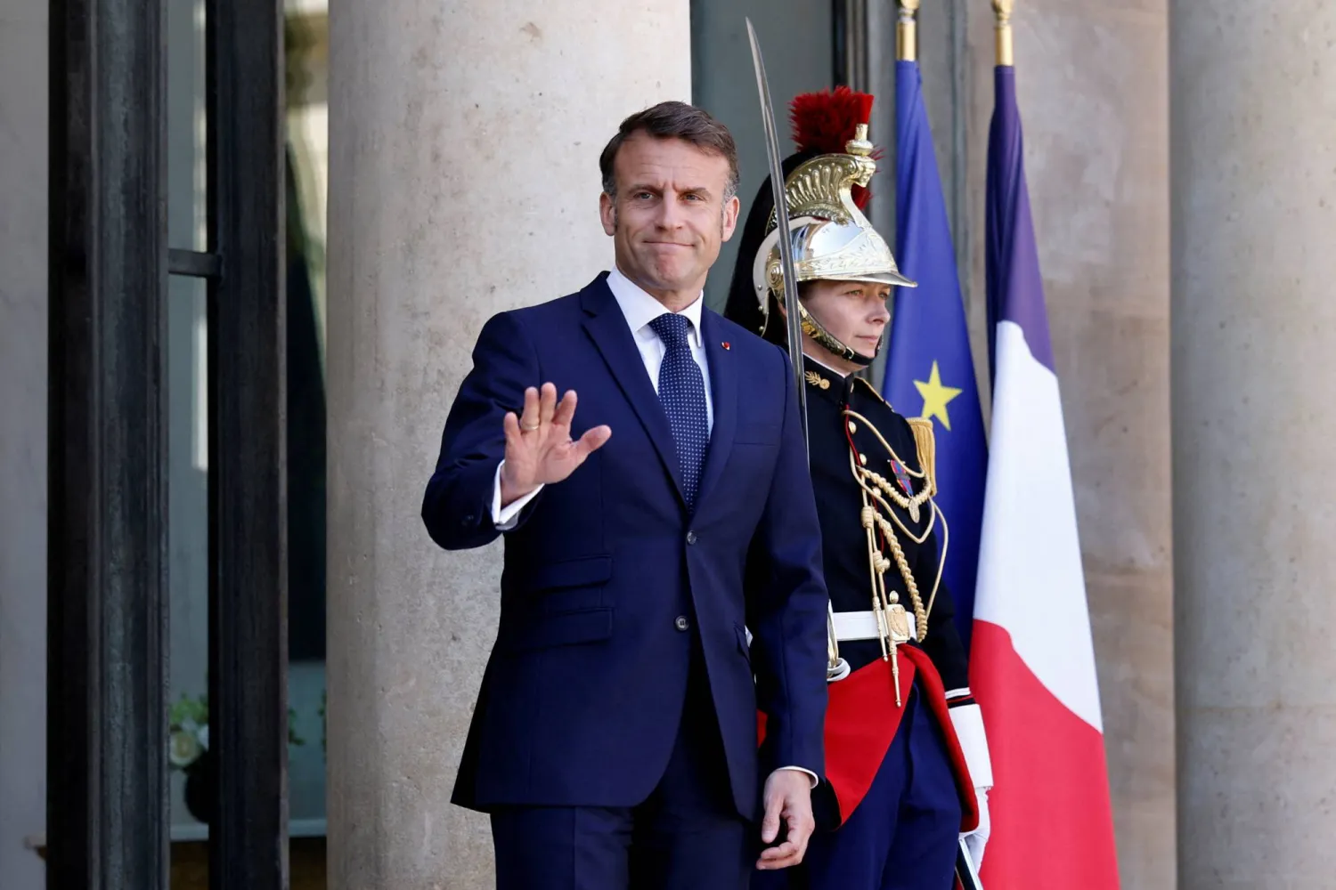 الرئيس الفرنسي إيمانويل ماكرون يلوح للصحافيين في قصر الإليزيه (رويترز)