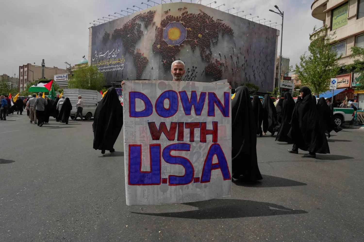 إيراني يحمل لافتة مكتوباً عليها «تسقط أميركا» في إحدى ساحات طهران يوم 11 أبريل 2025 (أ.ب)