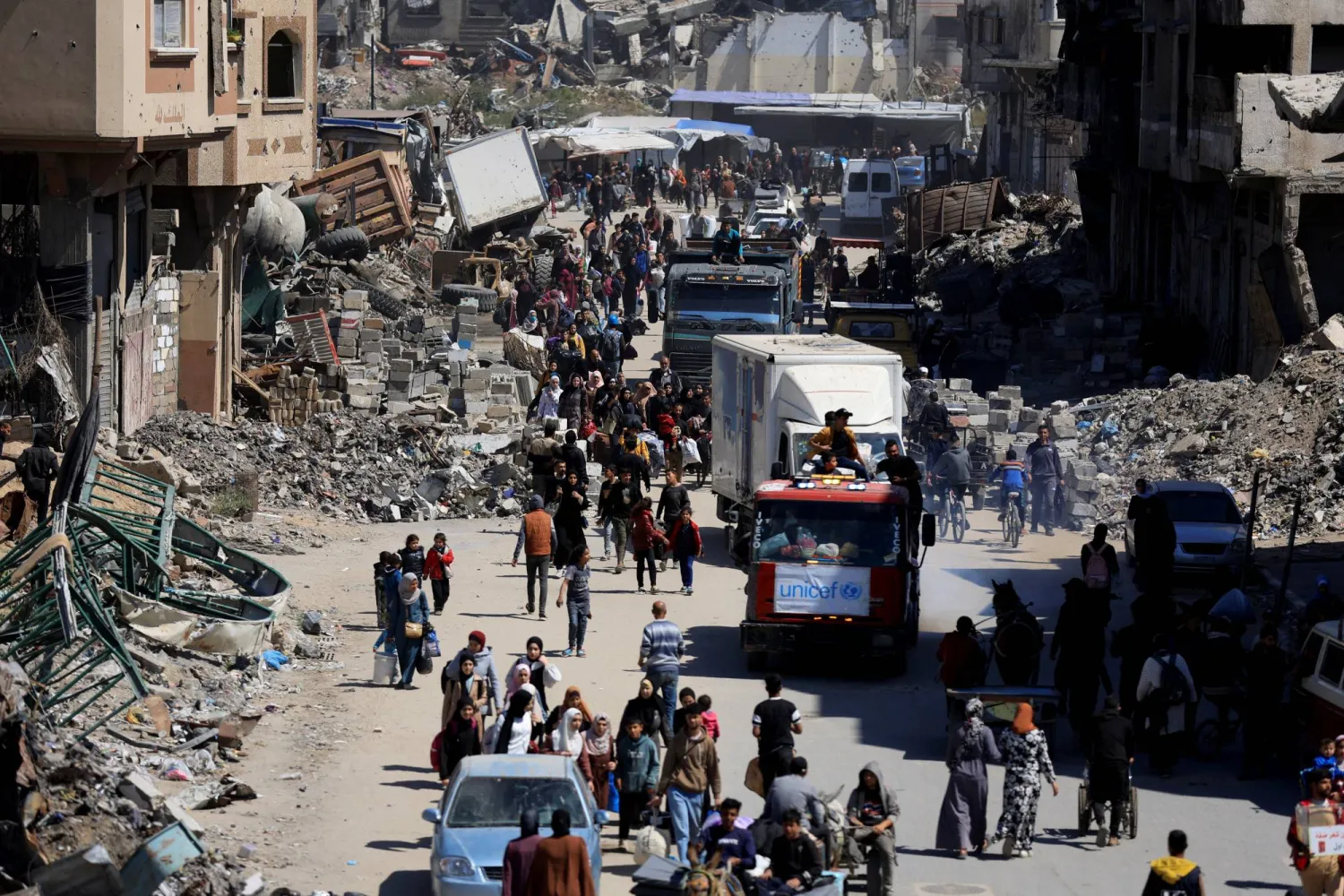 فلسطينيون يحملون أمتعتهم في أثناء فرارهم من مناطق في الجزء الشرقي من مدينة غزة (رويترز)