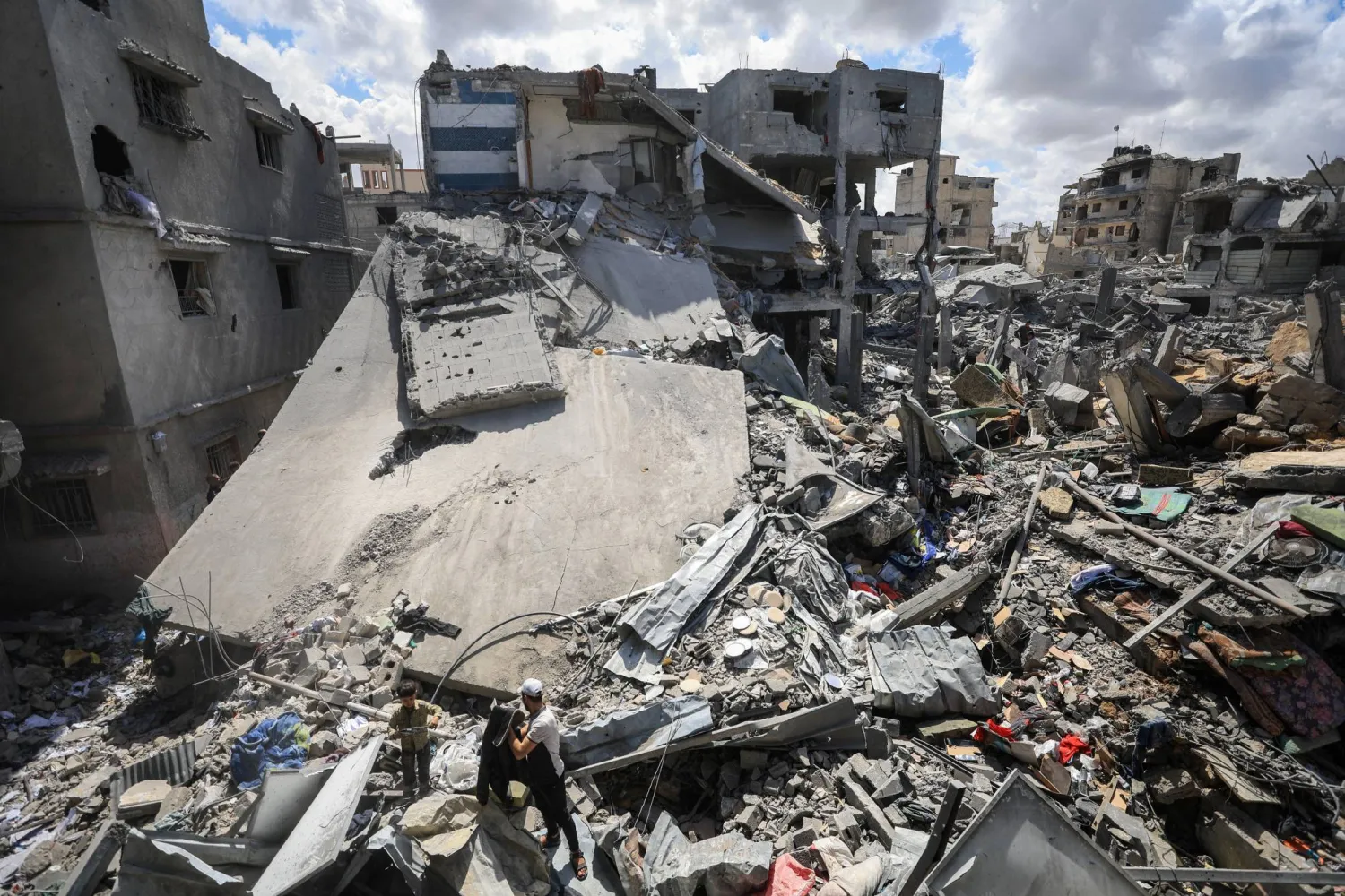 فلسطينيون يبحثون عن ضحايا محاصرين تحت الأنقاض في موقع غارة جوية إسرائيلية أصابت منزلاً بمدينة غزة (رويترز)