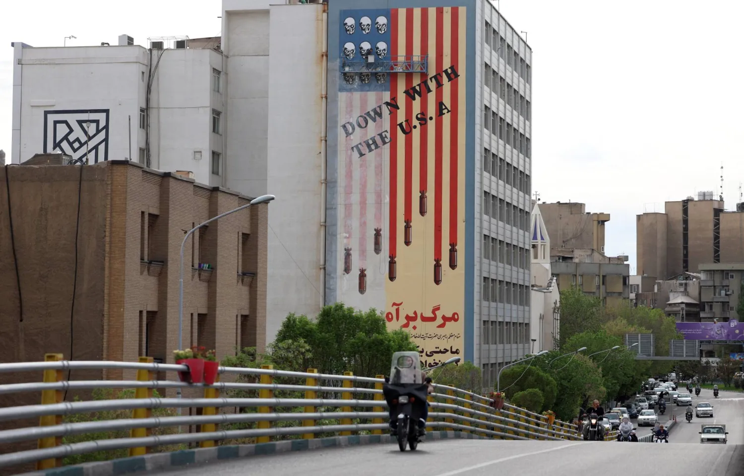 رسام إيراني يقوم بإعادة طلاء جدارية ضد الولايات المتحدة في طهران (إ.ب.أ)