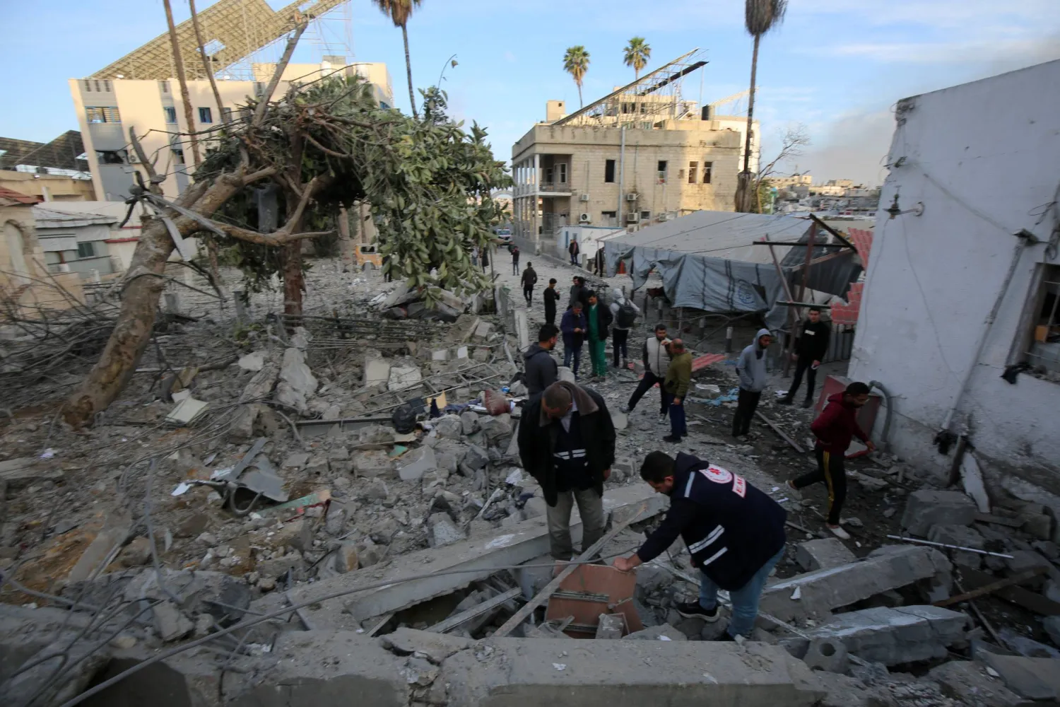 مسعفون وأشخاص يتفقدون آثار الدمار في محيط المستشفى (د.ب.أ)