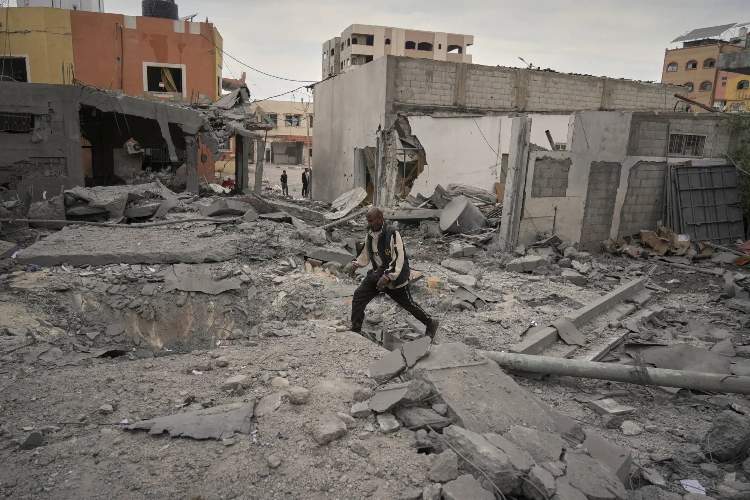 فلسطينى بالقرب من الحفرة التي خلفتها غارة للجيش الإسرائيلي أسفرت عن مقتل ثلاثة أشخاص على الأقل في دير البلح، وسط قطاع غزة (أ.ب)