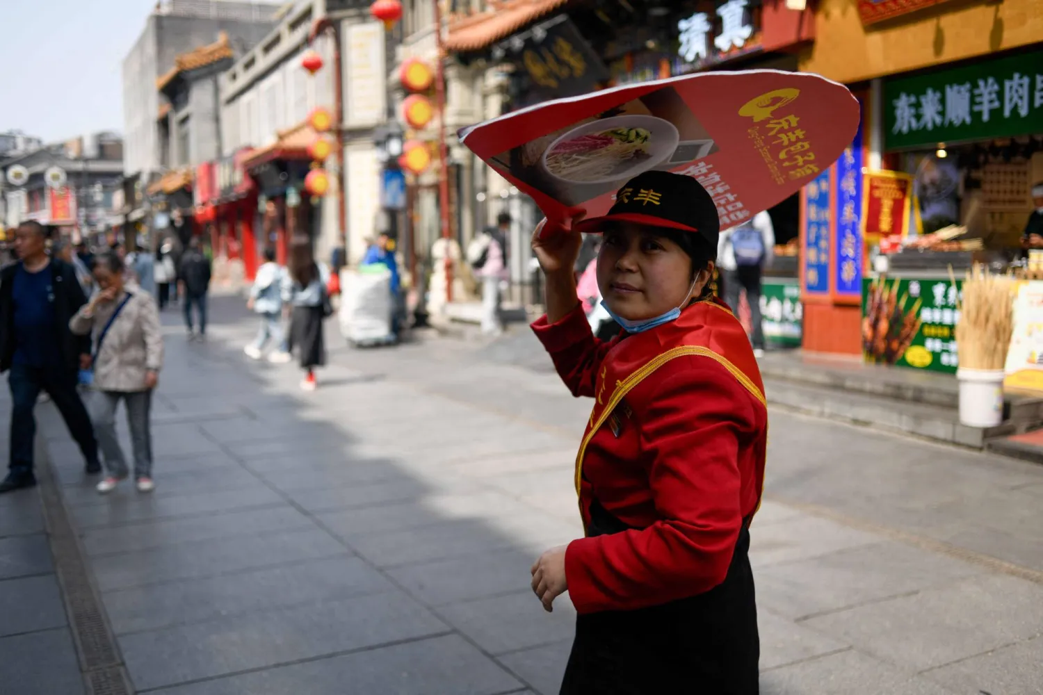 موظف ينتظر الزبائن في أحد شوارع بكين (أ.ف.ب)