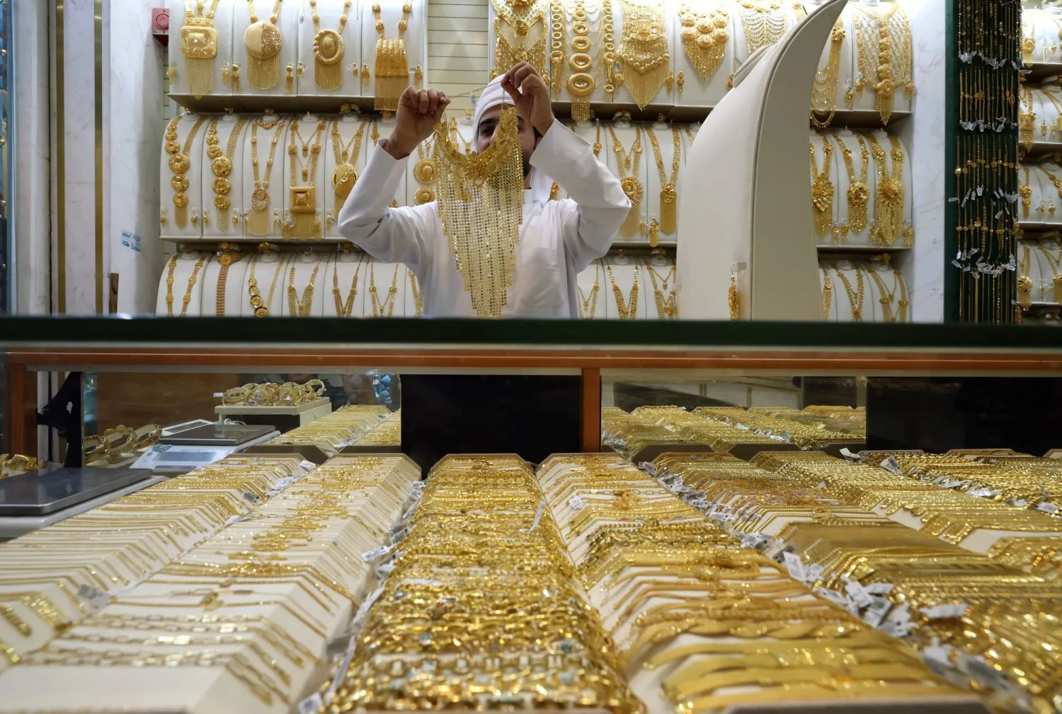 عرض قطعة ذهبية على أحد الزبائن بمتجر للمجوهرات داخل سوق الذهب في دبي (إ.ب.أ)