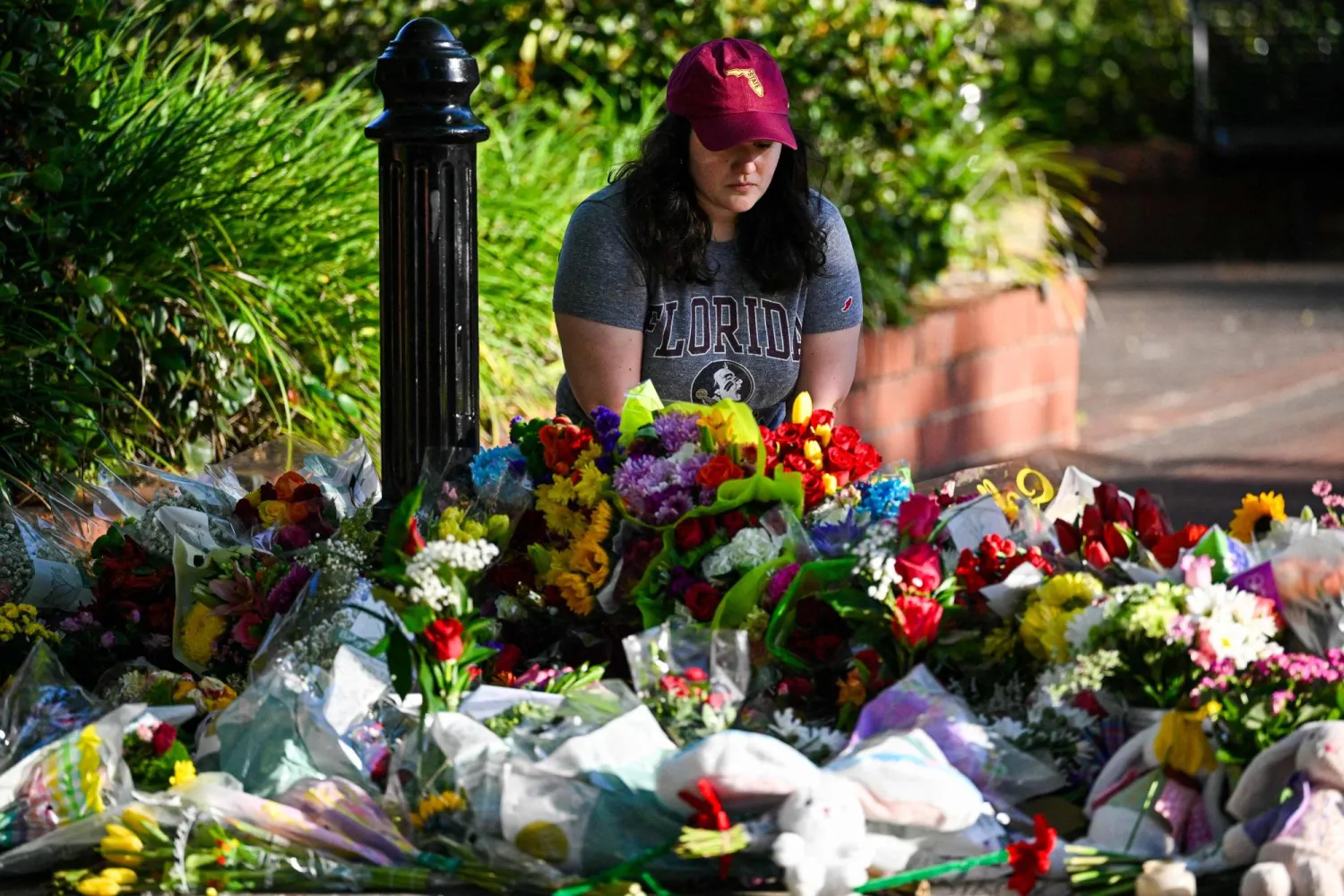 طالبة تضع وروداً تكريماً لضحايا إطلاق النار بجامعة فلوريدا 18 أبريل (أ.ف.ب)