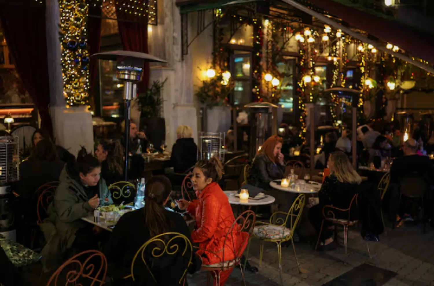 يتناول الناس الطعام في الهواء الطلق في أحد المطاعم بأثينا (رويترز)