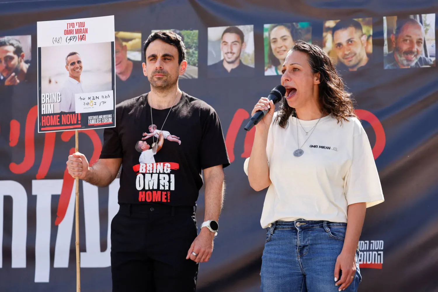 ليشاي ميران لافي زوجة الرهينة عمري ميران تتحدث بينما يقف أفراد عائلات الرهائن (رويترز)