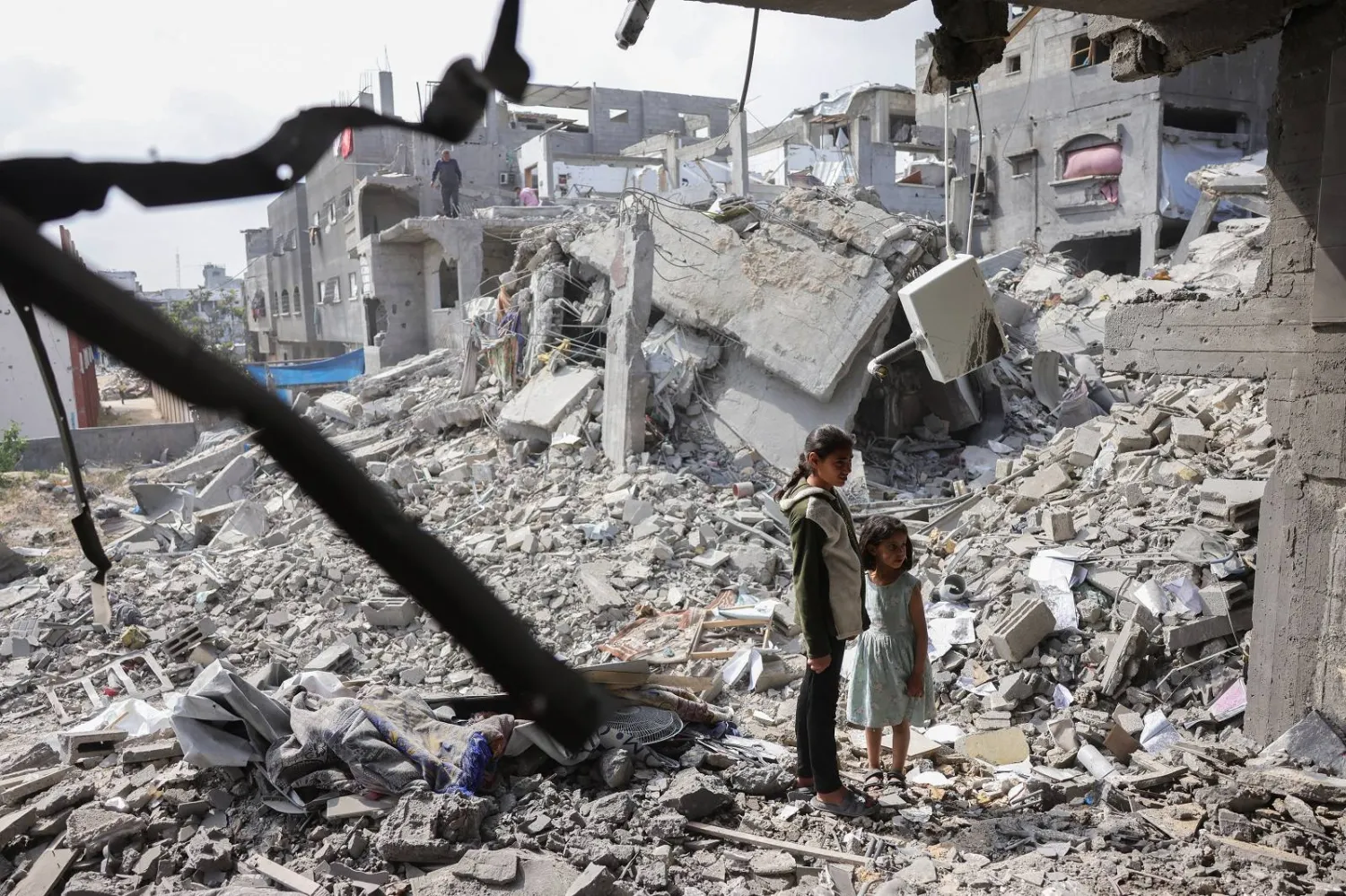 فتاتان فلسطينيتان تنظران إلى أنقاض مبانٍ دمرتها غارات إسرائيلية في بيت لاهيا شمال غزة (أ.ف.ب)
