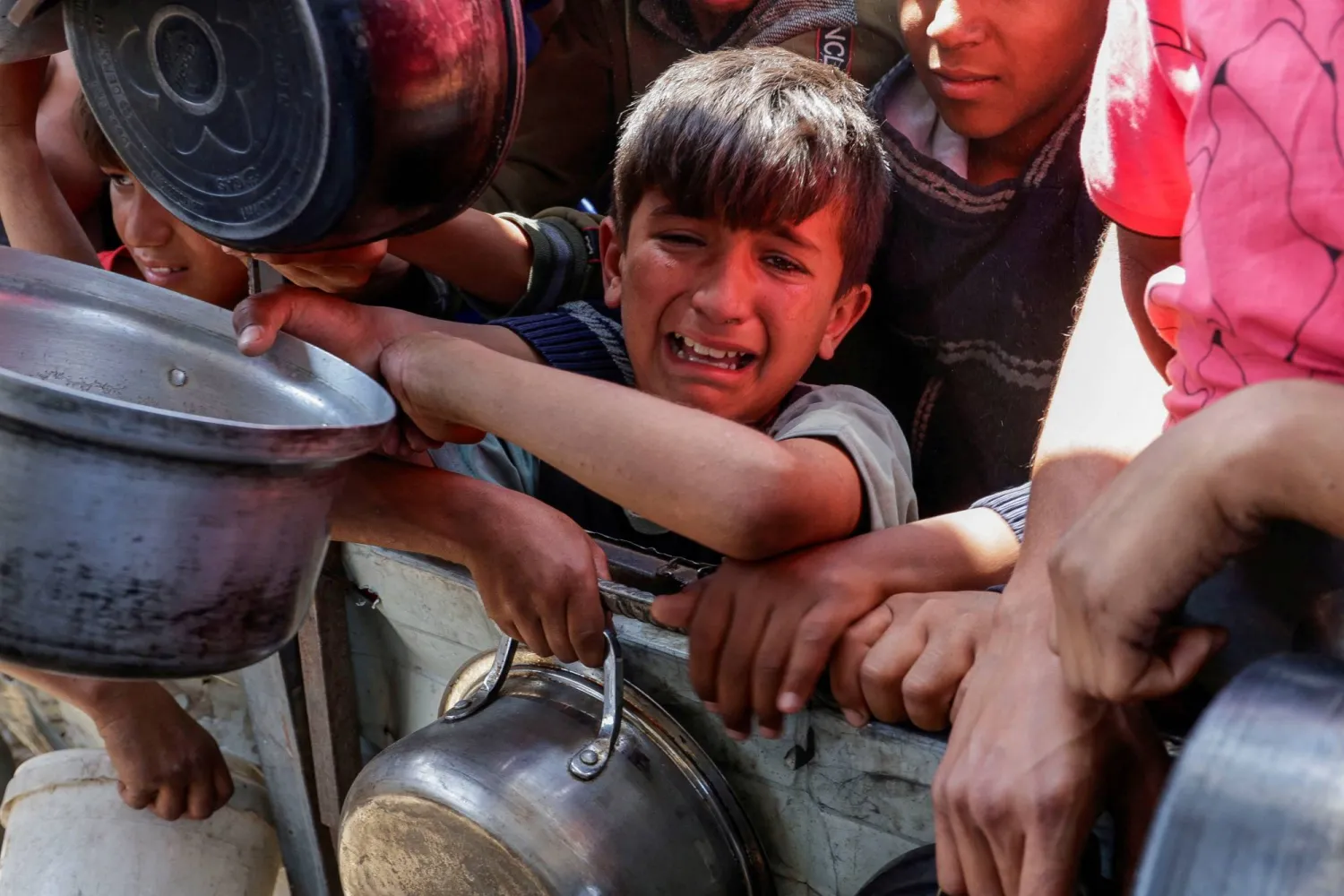 طفل فلسطيني يحاول الحصول على طعام أعدته جمعية خيرية في خان يونس جنوب قطاع غزة (رويترز)