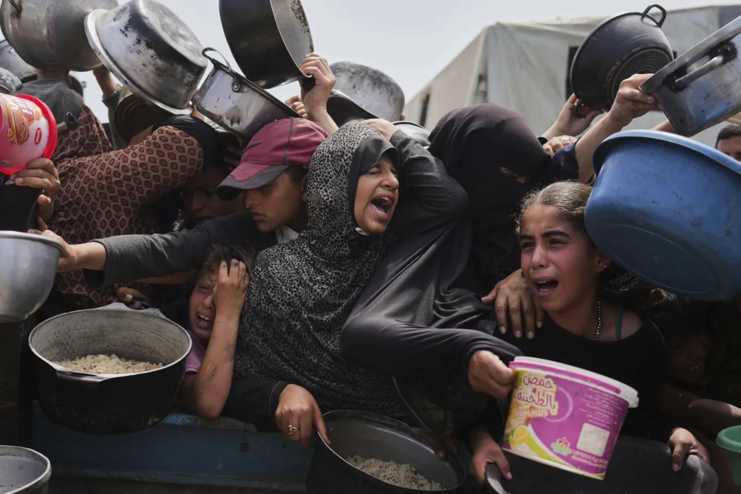 فلسطينيون يتلقون تبرعات غذائية بمركز توزيع في خان يونس بقطاع غزة (أ.ب)