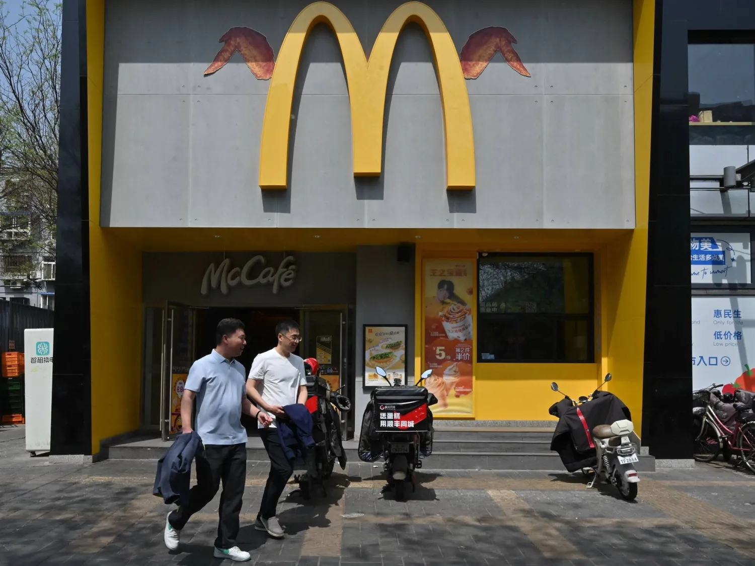 أشخاص يمرون أمام مطعم «ماكدونالدز» في بكين (أ.ف.ب)