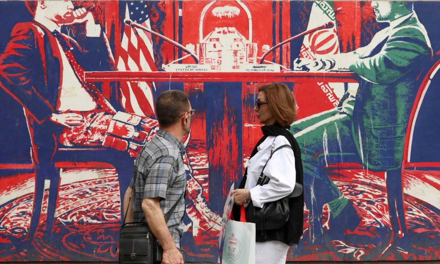 إيرانيان يمران أمام جدارية معادية للولايات المتحدة على حائط سفارتها السابقة في طهران (إ.ب.أ)