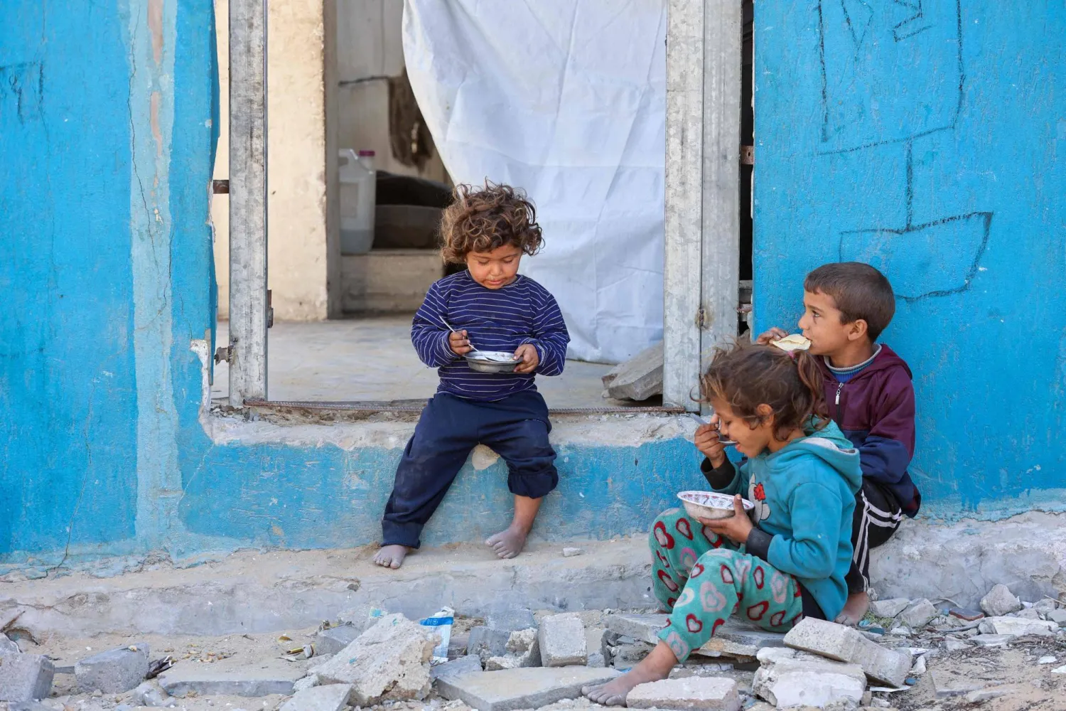 أطفال فلسطينيون بالقرب من مدخل منزل مدمر في مدينة غزة أمس (أ.ف.ب)