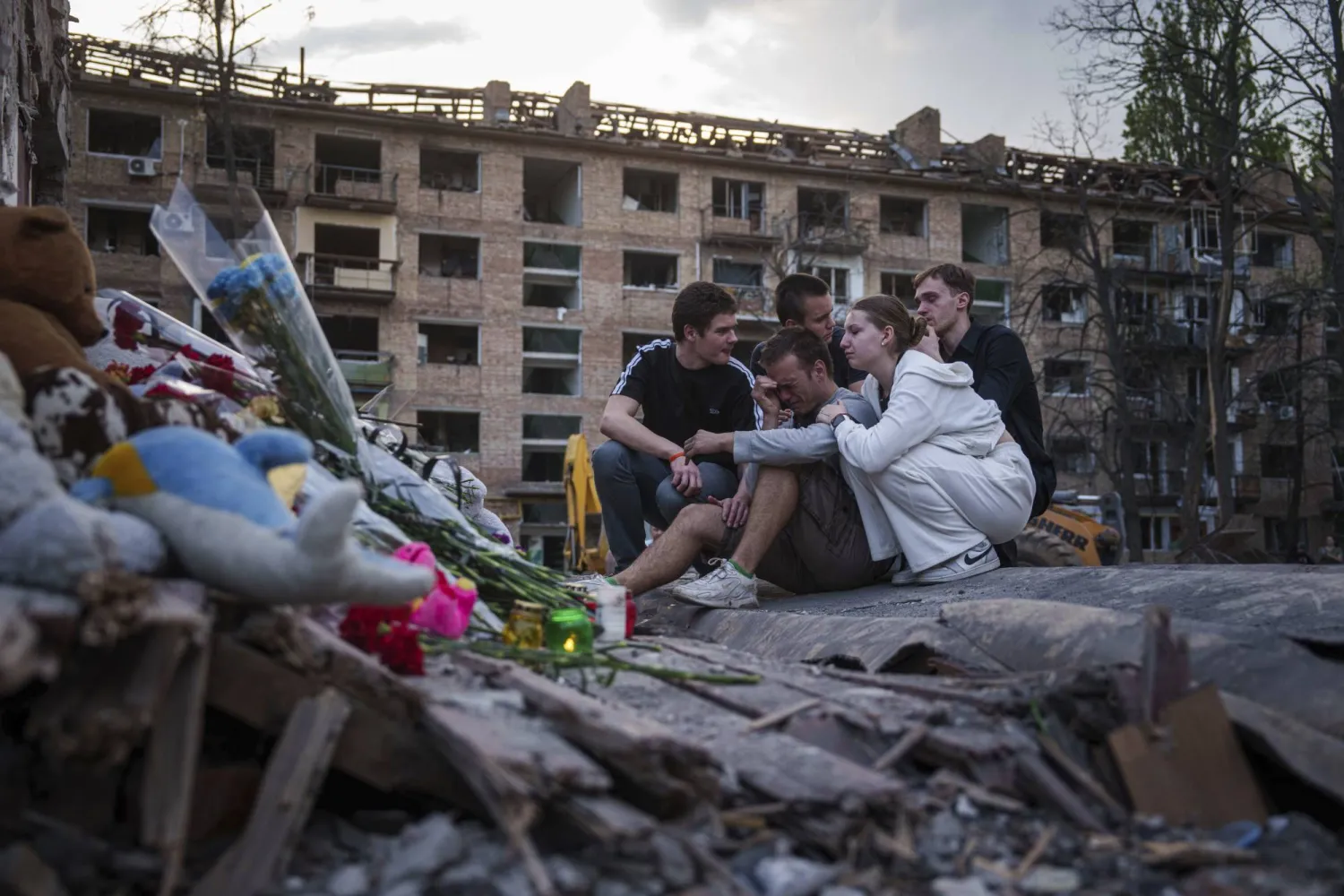 أوكرانيون يتجمعون بالقرب من أنقاض منزل في حي سكني بكييف تعرض لقصف روسي (أ.ب)