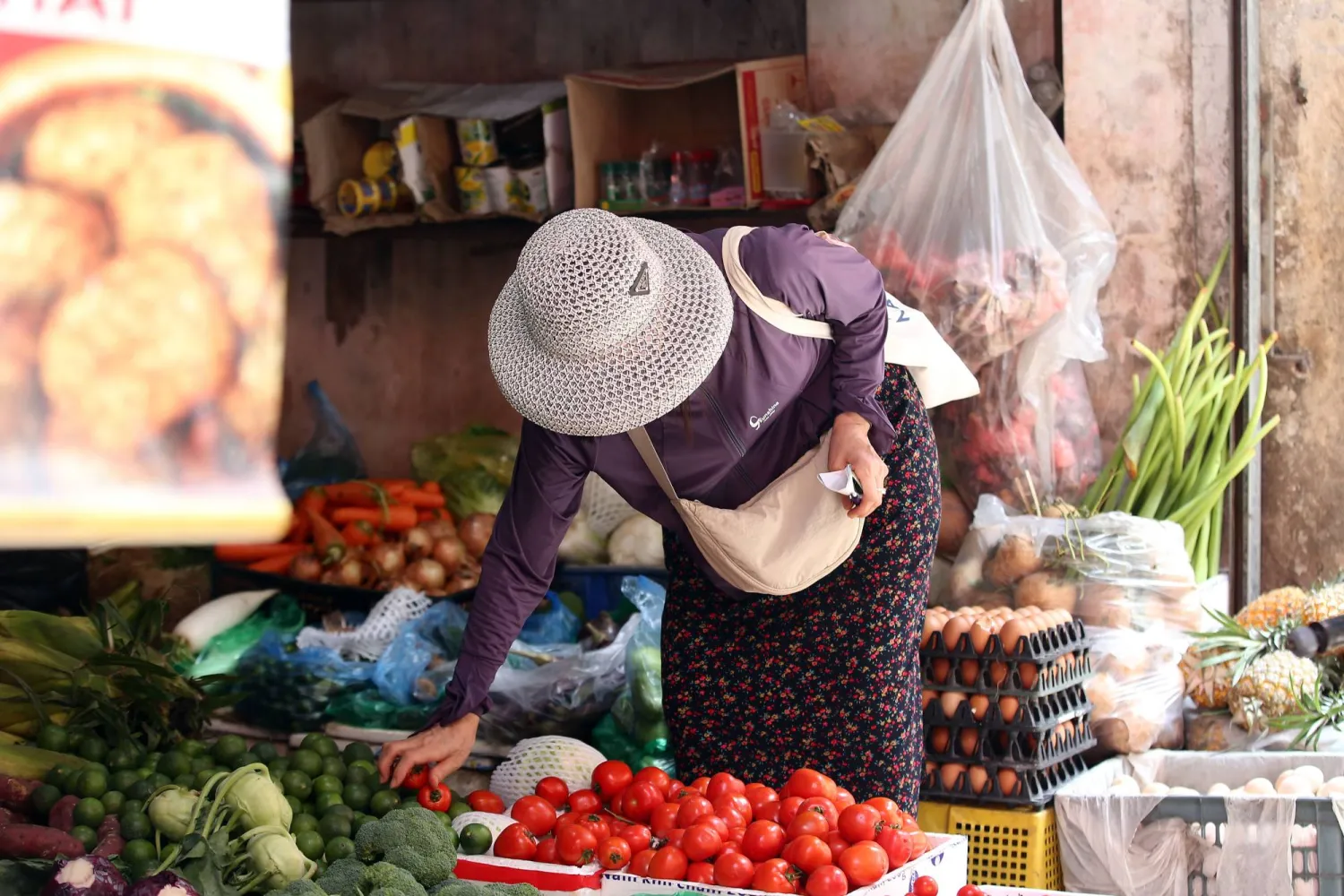 امرأة تشتري الطماطم من إحدى الأسواق في هانوي (إ.ب.أ)