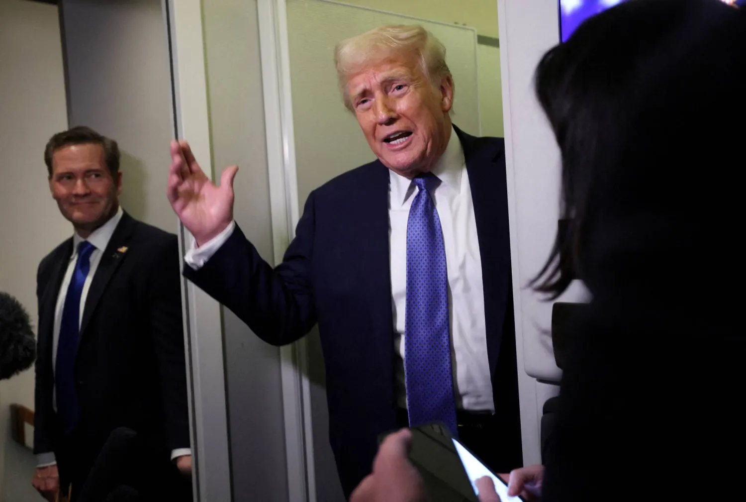 الرئيس الأميركي دونالد ترمب يتحدث للصحافيين على متن الطائرة الرئاسية وخلفه مستشار الأمن القومي مايك والتز (رويترز)