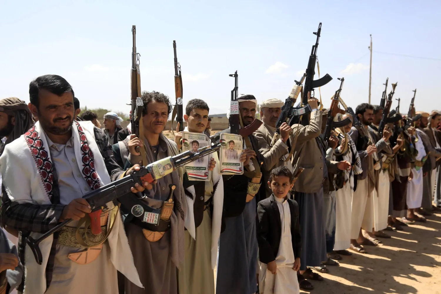 مسلحون حوثيون خلال تجمع في صنعاء لتشييع ضحايا غارات أميركية (إ.ب.أ)