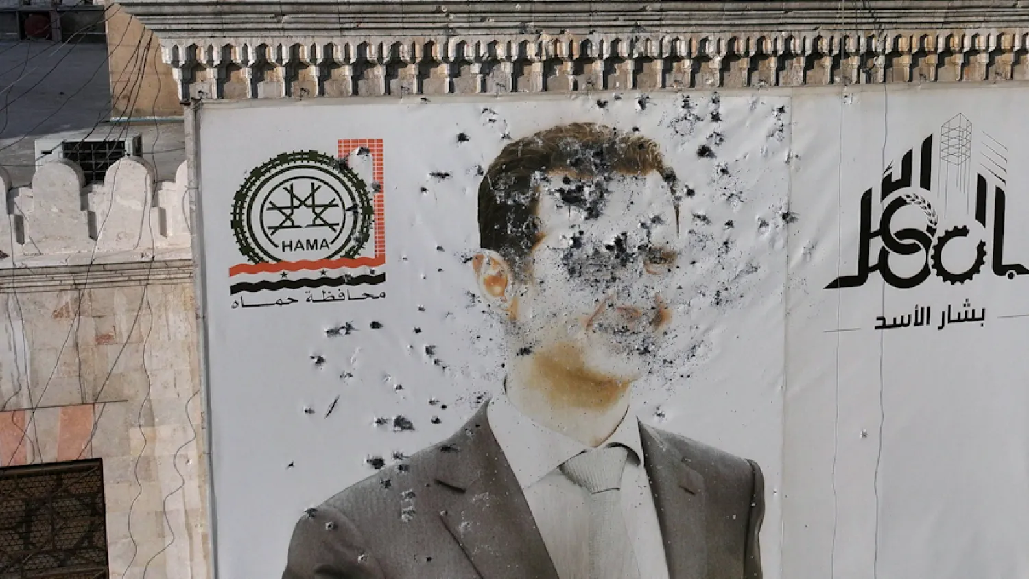 صورة بشار الأسد وقد طالها الرصاص على واجهة مكتب حكومي في أعقاب سيطرة المعارضة على حماة وسط سوريا في 6 ديسمبر 2024