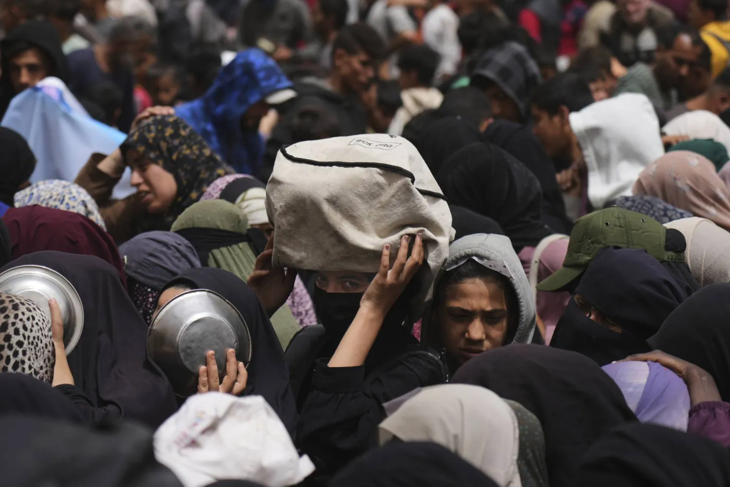 فلسطينيون ينتظرون الحصول على مساعدات غذائية في مخيم النصيرات بوسط قطاع غزة (أ.ب)