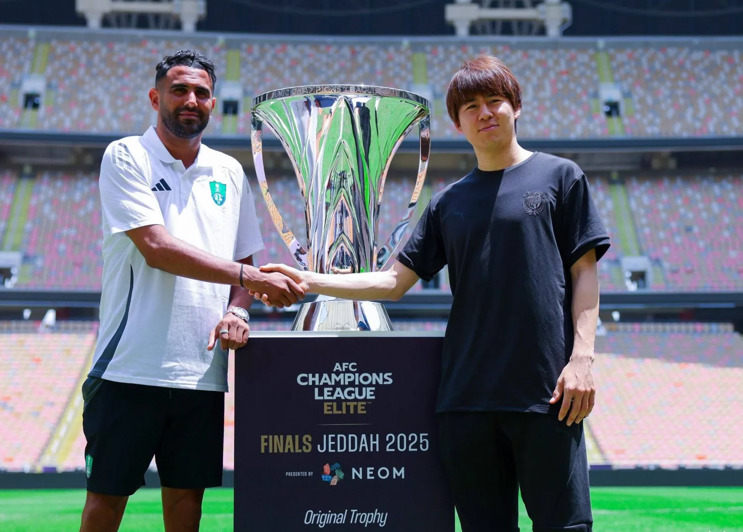 محرز وواكيزاكا يتصافحان وبينهما كأس البطولة (النادي الأهلي)