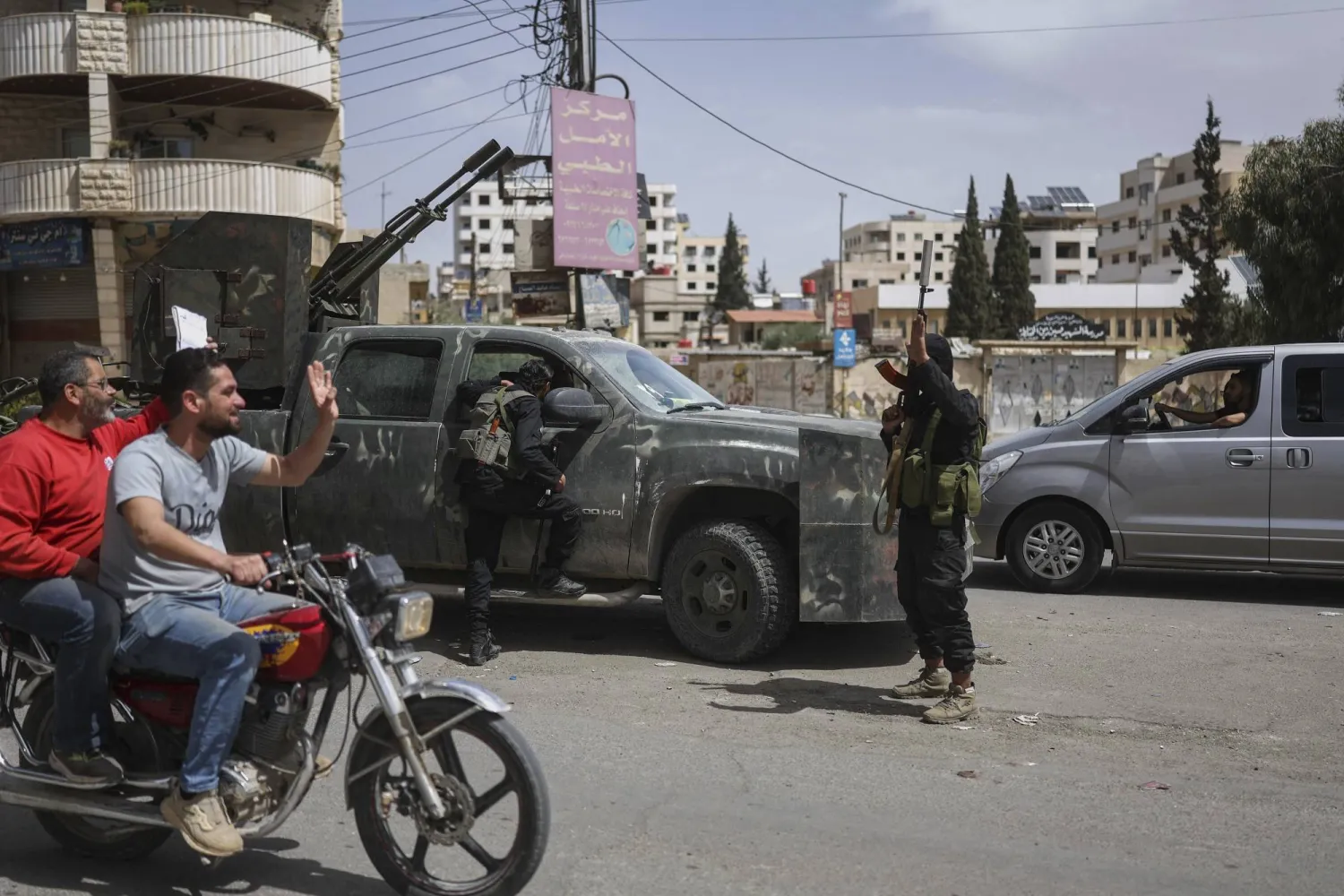 Syrian citizens salute members of Syria's security forces deployed in the town of Sahnaya, south of Damascus, Syria, Thursday, May 1, 2025. (AP Photo/Ghaith Alsayed)