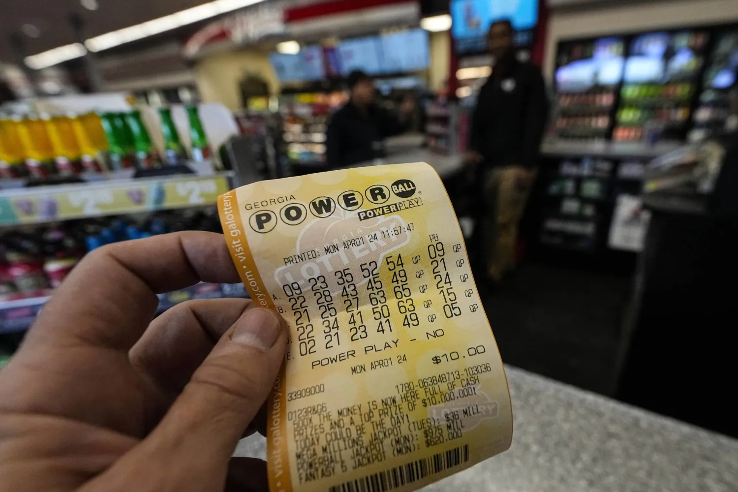 رجل يحمل تذكرة يانصيب Powerball داخل متجر صغير في أميركا (أ.ب)
