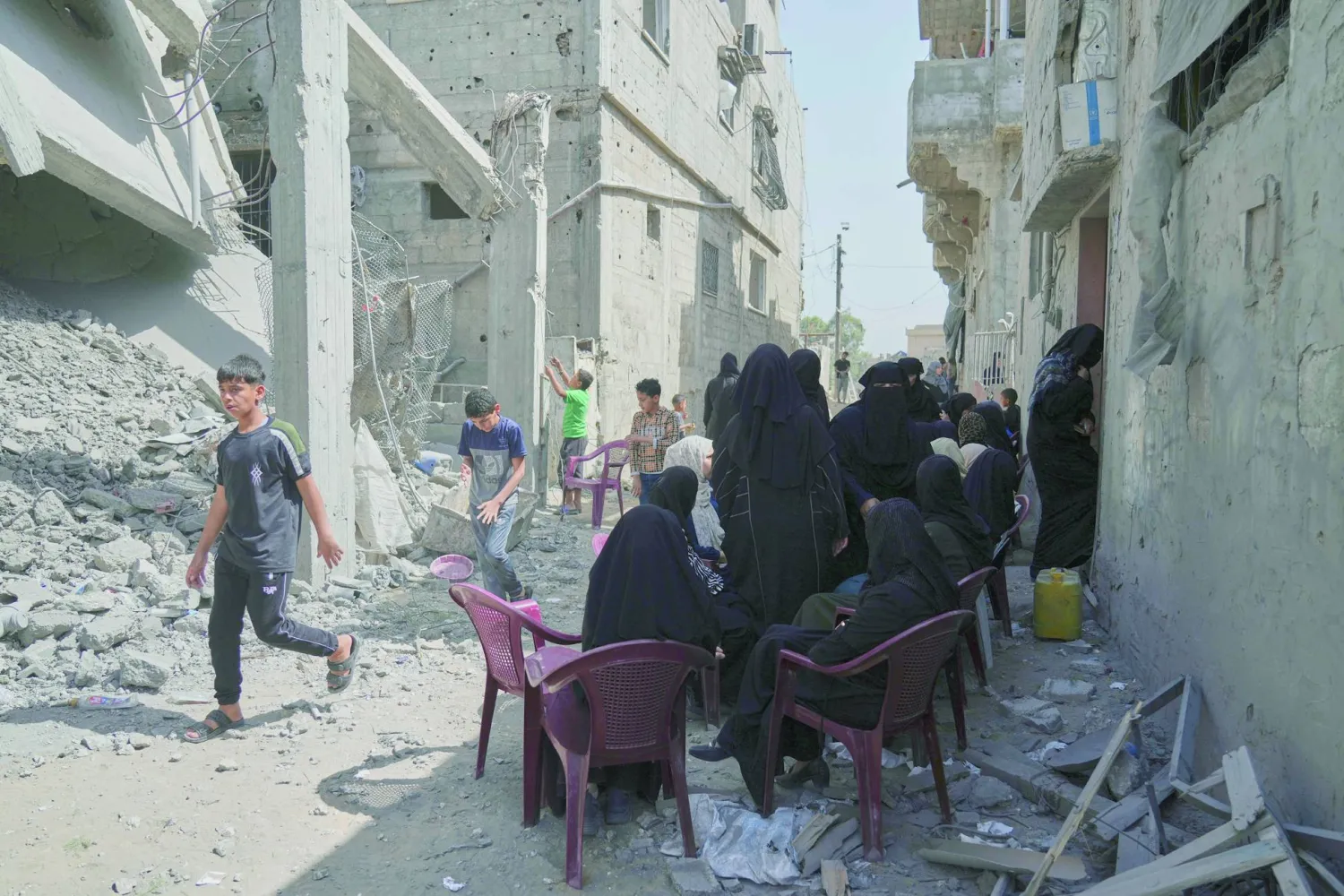 
فلسطينيون بجوار منزل مدمر جراء قصف إسرائيلي في خان يونس أمس (أ.ب)