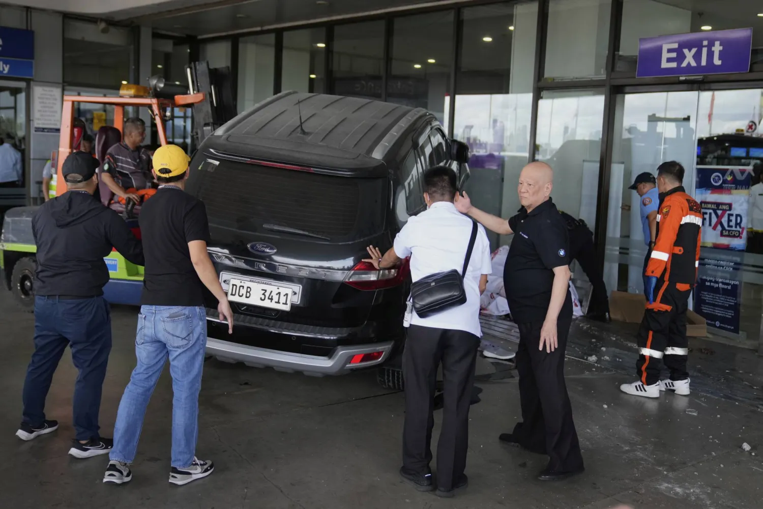 مسؤولون بمطار مانيلا يساعدون أفراد الطوارئ بعدما ارتطمت سيارة بمدخل صالة المغادرة (أ.ب)