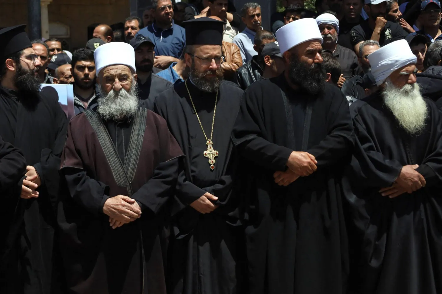رجال دين مسيحيون ومسلمون يحضرون جنازة أفراد من الطائفة الدرزية السورية قُتلوا باشتباكات طائفية حديثة في قرية صلخد بمحافظة السويداء (أ.ف.ب)