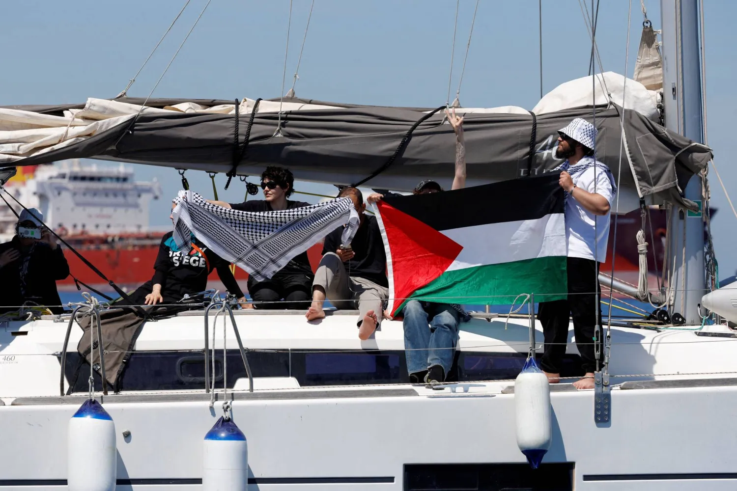 ناشطون يحملون علماً فلسطينياً على متن يخت يحمل إمدادات لغزة خارج المياه الإقليمية المالطية حيث مُنعوا من الاقتراب من سفينة «الضمير» التابعة لـ«أسطول الحرية» (رويترز)