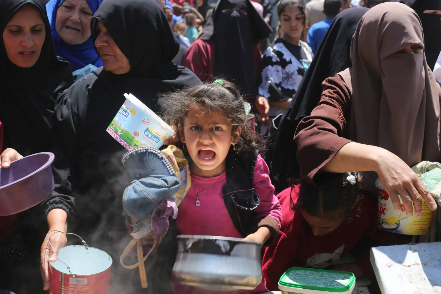 طفلة فلسطينية تصطفّ مع نساء آخريات للحصول على الطعام من تكية خيرية في مخيم النصيرات بقطاع غزة (أ.ف.ب)