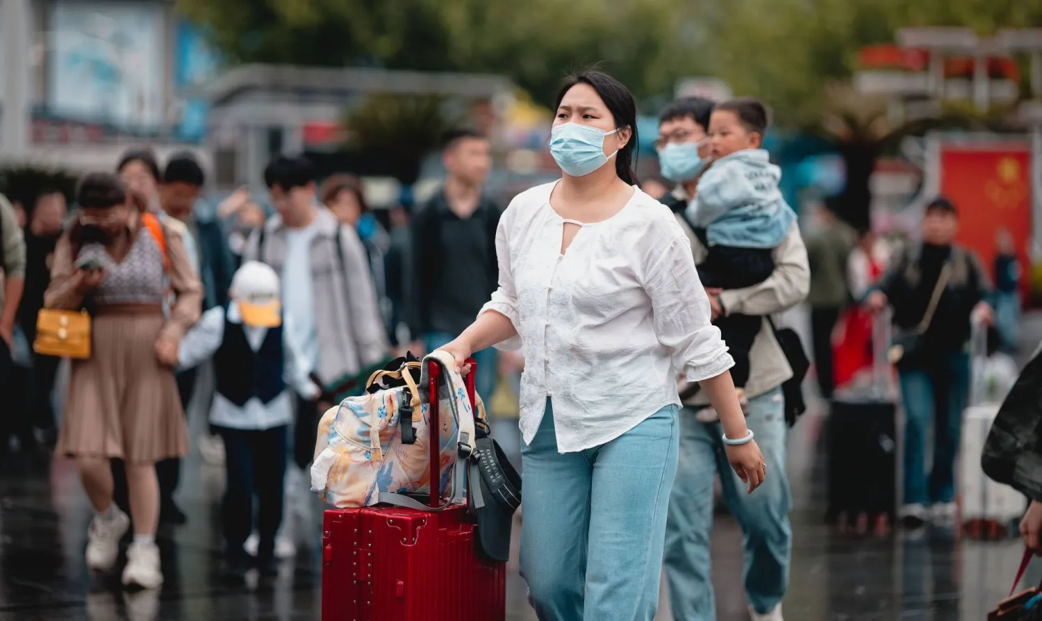 امرأة خارجة من محطة قطار بمدينة شنغهاي الصينية خلال الاحتفالات الممتدة بـ«عيد العمال»... (إ.ب.أ)